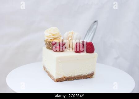 Tranche de cheesecake à la vanille classique New York avec framboise fraîche et cassis sur cakestan blanc. Banque D'Images