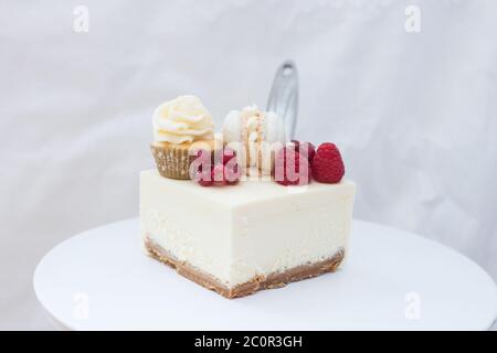 Tranche de cheesecake à la vanille classique New York avec framboise fraîche et cassis sur cakestan blanc. Banque D'Images