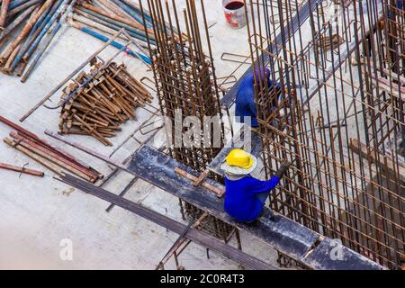 Les ouvriers de la construction fabriquent de grandes barres de renfort en acier sur le chantier de construction de la zone de construction. Banque D'Images