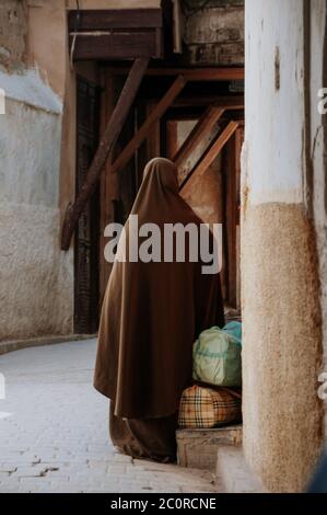 femme avec burka attendant dans une rue au maroc Banque D'Images