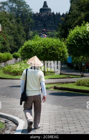 Homme avec chapeau de paille à marcher en direction de Borobudur temple Banque D'Images