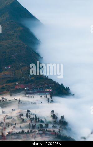 Couche de brume sur les montagnes et dans un village Banque D'Images