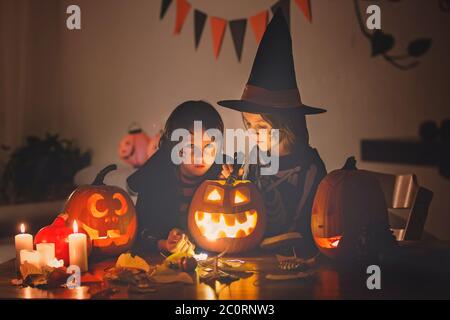 Enfants, frères garçons, jouant avec la citrouille sculptée à la maison à Halloween, faisant la potion magique Banque D'Images