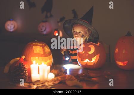 Adorable enfant, petite fille, jouant avec la citrouille sculptée d'Halloween et la décoration à la maison Banque D'Images