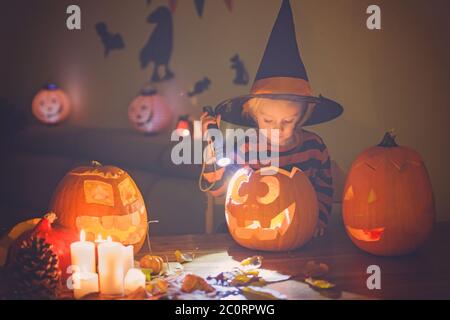 Adorable enfant, petite fille, jouant avec la citrouille sculptée d'Halloween et la décoration à la maison Banque D'Images