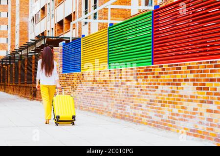 femme sur le dos avec une valise jaune qui descend la rue Banque D'Images