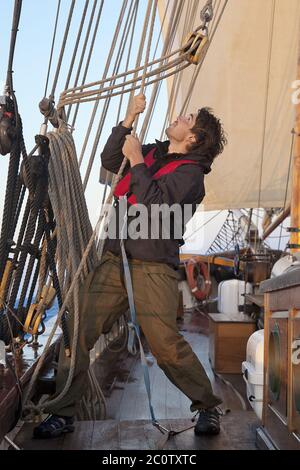 Jeune marin sur le pont d'un navire à voiles de levage