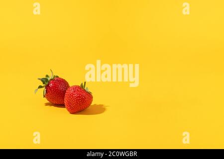 Composition estivale fruits, baies. Deux fraises fraîchement mûres sur fond jaune Banque D'Images