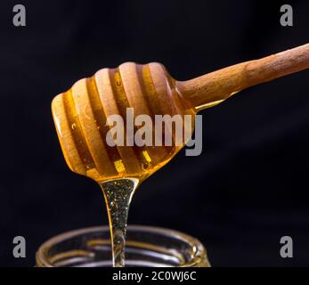 Goutte de miel dans un pot sur foncé Banque D'Images