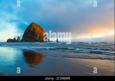 La lumière dorée du coucher de soleil sur Haystack Rock sur Cannon Beach, le long de la côte de l'Oregon Banque D'Images