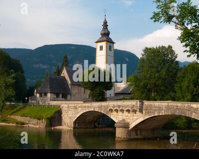 Clocher de l'église et le pont de pierre, à lac de Bohinj dans Ribicev village alpin Laz, Slovénie Banque D'Images