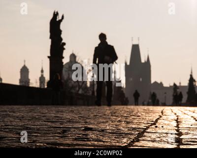 Les gens marchent sur le pont Charles tôt le matin, Prague, République tchèque. Axé sur les pavés. Les gens et l'architecture ne sont pas concentrés. Faible profondeur de champ. Banque D'Images