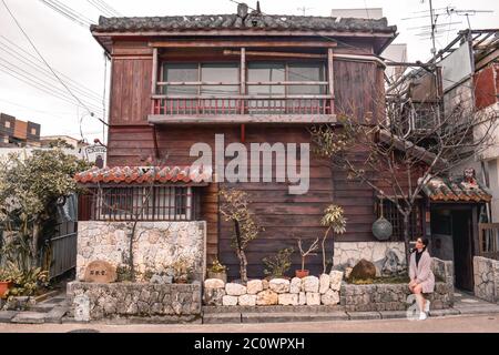 Fille assise devant une maison japonaise traditionnelle en bois à Naha Okinawa Japon Banque D'Images