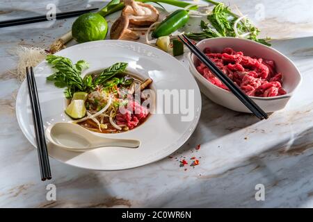 Soupe vietnamienne traditionnelle de nouilles de bœuf au pho bo servie avec des nouilles, des champignons de coriandre au basilic et des pousses de haricots Banque D'Images