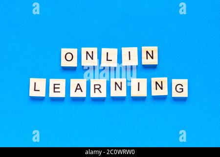 concepts d'apprentissage en ligne écrits en lettres de bois sur fond bleu. vue de dessus d'une mise en page plate, école en ligne. une nouvelle forme d'apprentissage Banque D'Images