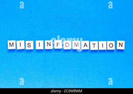 mystification écrite en lettres de bois sur fond bleu, vue de dessus, tromperie, fausse information, fausses nouvelles, disposition plate Banque D'Images