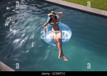 Femme de race mixte appréciant sa piscine pendant la pandémie de coronavirus covid19 Banque D'Images