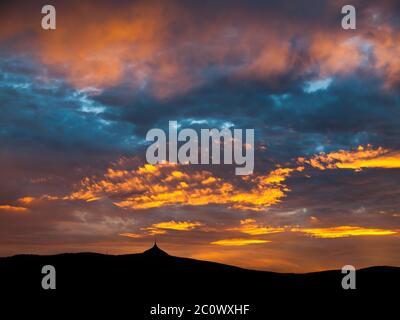 Ciel spectaculaire au coucher du soleil avec nuages illuminés dans les montagnes. Silhouette noire foncé de la crête de montagne et de la tour de l'émetteur de la Jested au bas. Banque D'Images