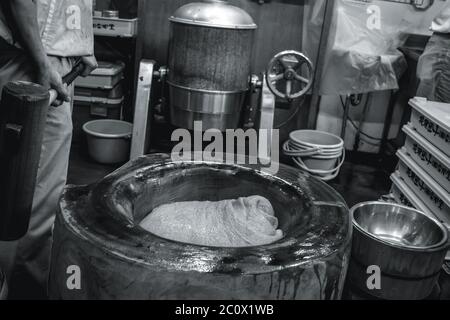 Homme avec un gros marteau préparant le mochi traditionnel japonais de riz collant Banque D'Images