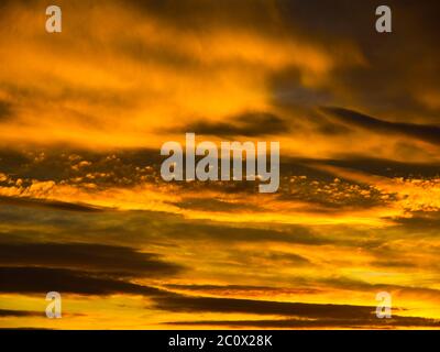 Ciel doré spectaculaire avec nuages illuminés au coucher du soleil. Banque D'Images