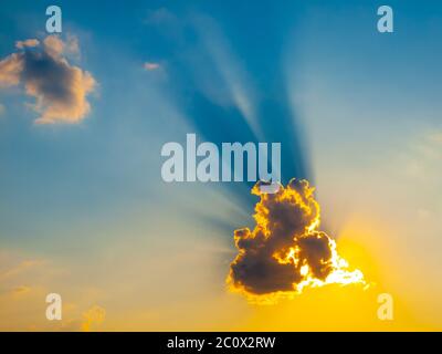 Le soleil brille du soleil du soir derrière un petit nuage. Banque D'Images