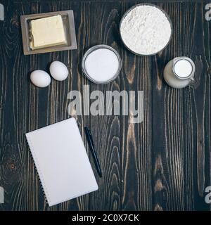 vue de dessus de livre de cuisine, farine, oeufs, sucre et lait sur fond de bois Banque D'Images