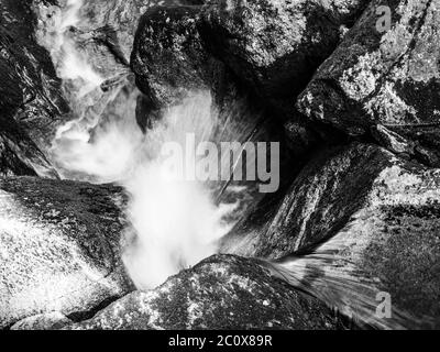 Cascade d'eau de petite crique entre des pierres de mousse. Image en noir et blanc à exposition longue. Banque D'Images