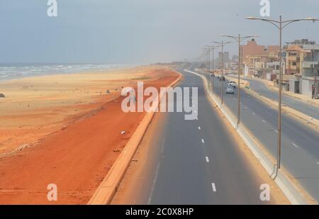 Route côtière presque vide et plage également vide dans le quartier de Guediawaye, Dakar, Sénégal Banque D'Images