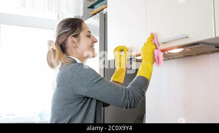 Portrait d'une jeune femme souriante et heureuse qui nettoie et lustre les surfaces de la cuisine tout en faisant des travaux ménagers Banque D'Images