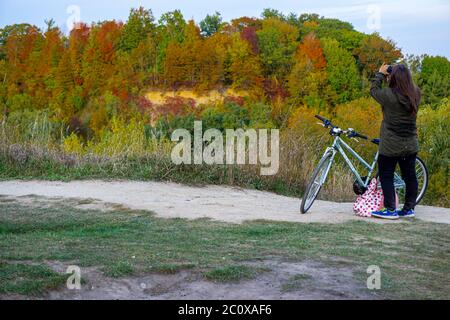 Falaises de Scarborough, Toronto, Canada, octobre 2016 - vue arrière d'une femme debout à vélo pour prendre des photos des couleurs d'automne de la forêt Banque D'Images