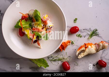 salade saine avec chair de crabe, pamplemousse et tomates sur fond bleu blanc vue latérale Banque D'Images