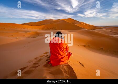 Une personne assise au sommet de dunes de sable et prenant des photos du désert du Sahara au Maroc Banque D'Images