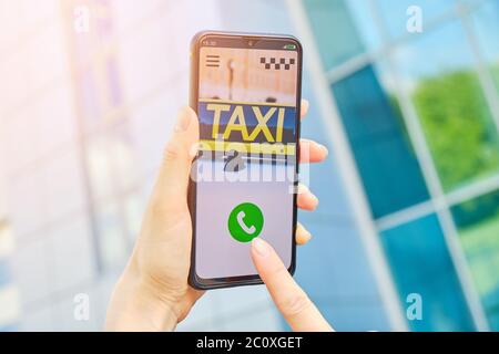 Le concept d'appeler un taxi par l'application - une main tient un smartphone dans la rue Banque D'Images