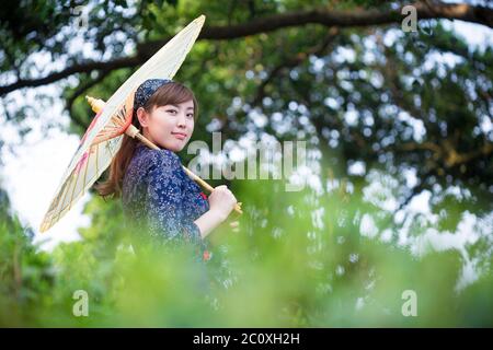 Belle fille asiatique est titulaire d'Umbrella dans la plantation de thé vert Banque D'Images