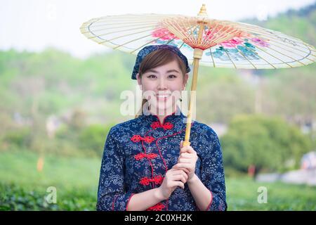 Belle fille asiatique est titulaire d'Umbrella dans la plantation de thé vert Banque D'Images