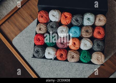 Prise de vue aérienne d'une boîte pleine de 24 peloins de couleur différente de fil de coton amigurumi, foyer sélectif. Banque D'Images