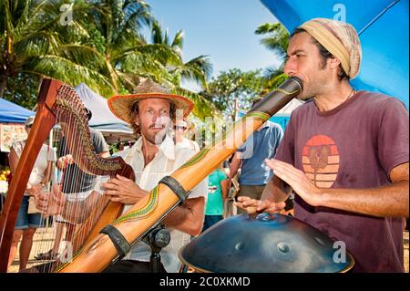 Deux musiciens en compagnie de Harp et de didgeridoo se sont délités sur les marchés extérieurs de Port Douglas, dans le Queensland du Grand Nord, en Australie. Banque D'Images