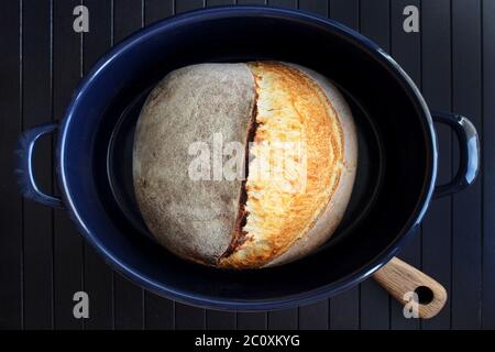 Pain au levain dans un moule bleu sur fond noir. Photographie de pain maison. Illustration de haute qualité Banque D'Images