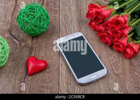 Téléphone mobile, coeur rouge et roses sur fond en bois Banque D'Images