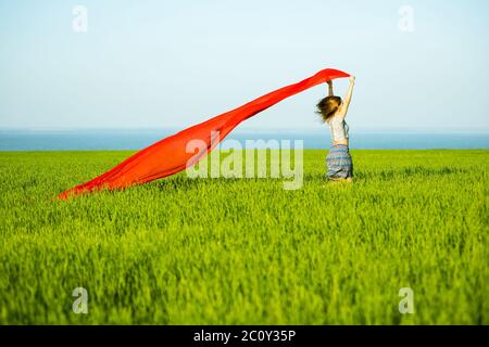 Jeune femme heureuse en champ de blé avec le tissu. Vie d'été Banque D'Images