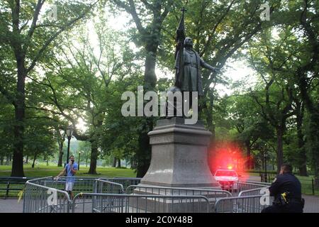11 juin 2020, New York, New York, Etats-Unis: Cet officier du NYPD surveille la statue de Christophe Colomb encadrée par des portes au centre d'une plaza dans Central Park. Le monument, étiqueté la semaine dernière et nettoyé depuis, est sous surveillance de nuit et de jour comme un autre qui surplombe Columbus Circle à New York. Les questions sur la suppression des statues dédiées à l'explorateur italien ont proliféré à la lumière du mal qu'elles ont fait aux autochtones tandis que quelques personnages confédérés ont été enlevés. Une statue de Columbus a été tirée et jeté dans un lac à Richmond, en Virginie, et un a été décapité Banque D'Images