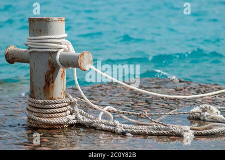 Amarrage bateau rouillé bollard avec cordes et claire de la mer turquouse ocen sur l'eau contexte Banque D'Images