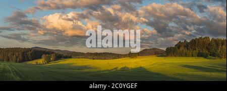 magnifique coucher de soleil paysage avec des prairies, des arbres, des forêts, en arrière-plan collines boisées et ciel bleu avec des nuages Banque D'Images