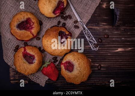 Muffin aux fraises et grains de café sur un panneau en bois sur fond de bois sombre. Muffins au chocolat sur fond sombre, mise au point sélective. Banque D'Images