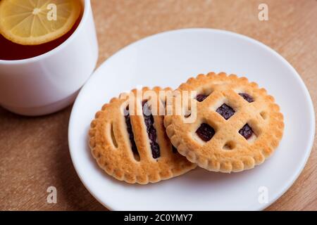 Tasse de thé et de citron, les biscuits avec de la confiture dans une soucoupe sur la table view Banque D'Images