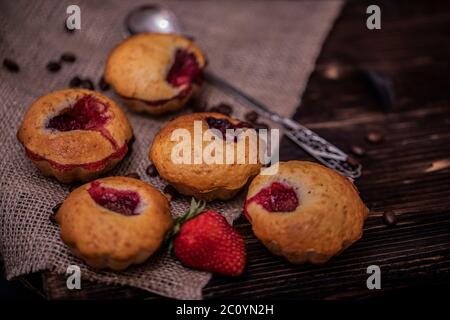 Muffin aux fraises et grains de café sur un panneau en bois sur fond de bois sombre. Muffins au chocolat sur fond sombre, mise au point sélective. Banque D'Images