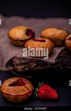 Muffin aux fraises et grains de café sur un panneau en bois sur fond de bois sombre. Muffins au chocolat sur fond sombre, mise au point sélective. Banque D'Images