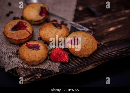 Muffin aux fraises et grains de café sur un panneau en bois sur fond de bois sombre. Muffins au chocolat sur fond sombre, mise au point sélective. Banque D'Images