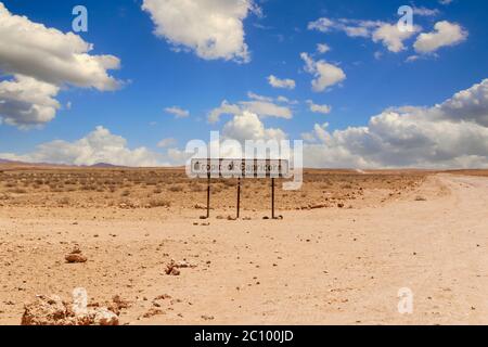 Tropic de Capricorne signe à une route de terre dans le désert en Namibie sous un ciel bleu avec quelques nuages sur le sable par une journée chaude. Banque D'Images