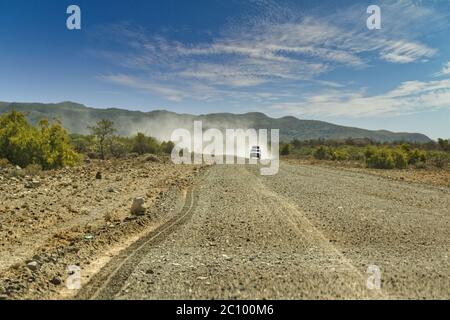 Camionnette avec tente sur toit roulant rapidement sur une longue route droite dans le désert. Journée chaude et ensoleillée avec ciel bleu. Afrique-Namibie Banque D'Images